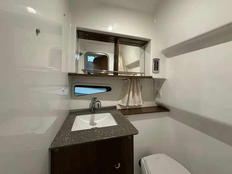 Slide: The Image of 2021 Four Winns Vista 275 bathroom with modern sink, mirror, and compact toilet. - 20
