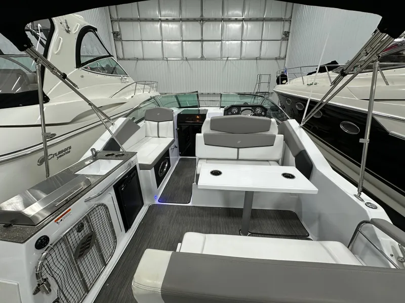 Slide: The Image of 2021 Four Winns Vista 275 boat interior with seating and kitchenette in a showroom. - 4