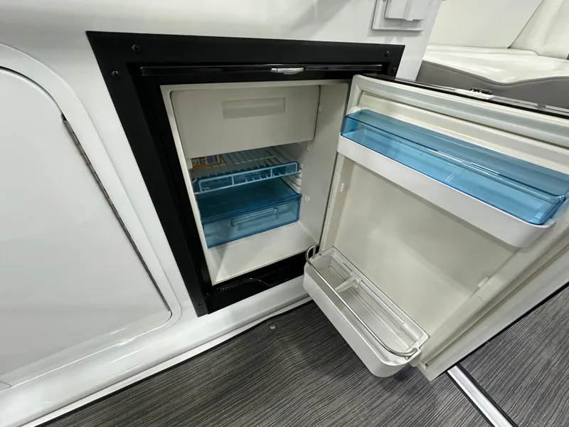 Slide: The Image of Open mini fridge inside 2021 Four Winns Vista 275 boat, showing interior shelves. - 7