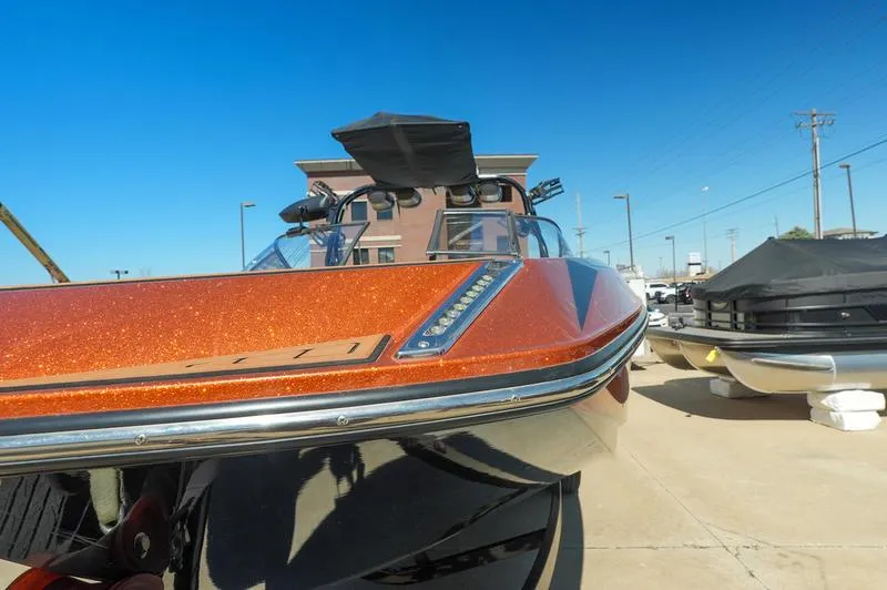 Slide: The Image of 2015 Nautique Super Air G23 boat with orange finish, docked under clear blue sky. - 18