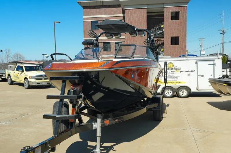 Slide: The Image of 2015 Nautique Super Air G23 boat on trailer, parked outdoors near a building. - 20