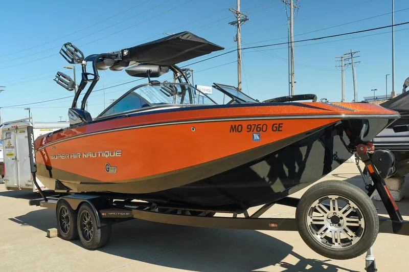 Slide: The Image of 2015 Nautique Super Air G23 boat on trailer, orange and black design, parked outdoors. - 21