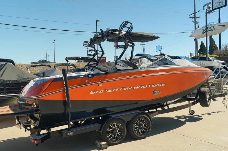 Slide: The Image of 2015 Nautique Super Air G23 boat on trailer, orange and black design, parked outdoors. - 22