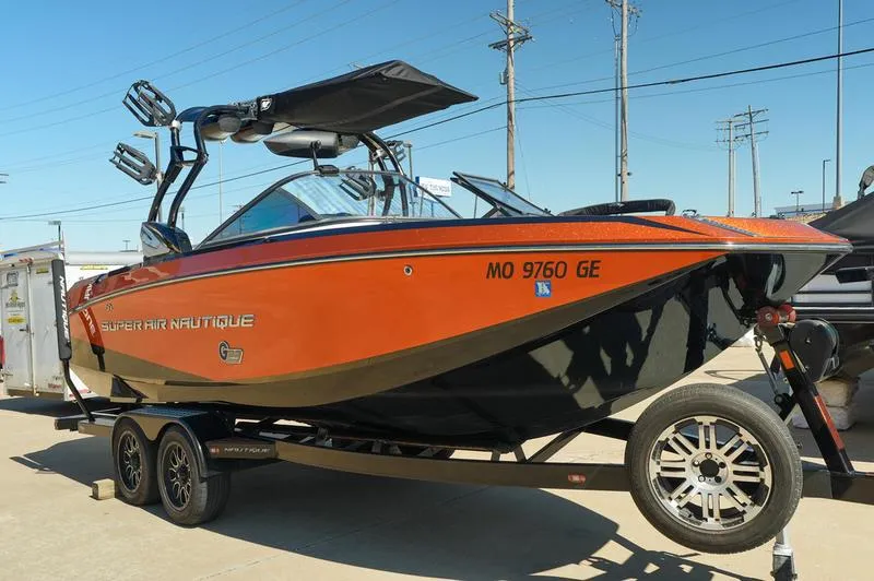 Slide: The Image of 2015 Nautique Super Air G23 boat on trailer, orange and black design, parked outdoors. - 8