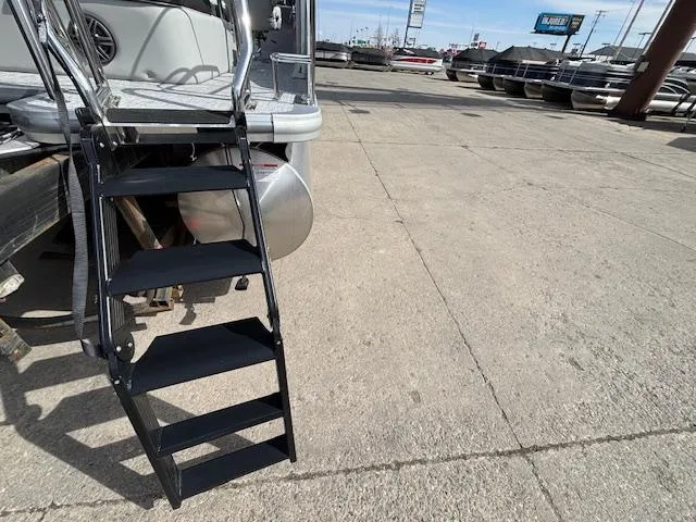 Slide: The Image of Stairs leading to a 2025 Harris Cruiser 210 SLDH boat on a concrete lot. - 26