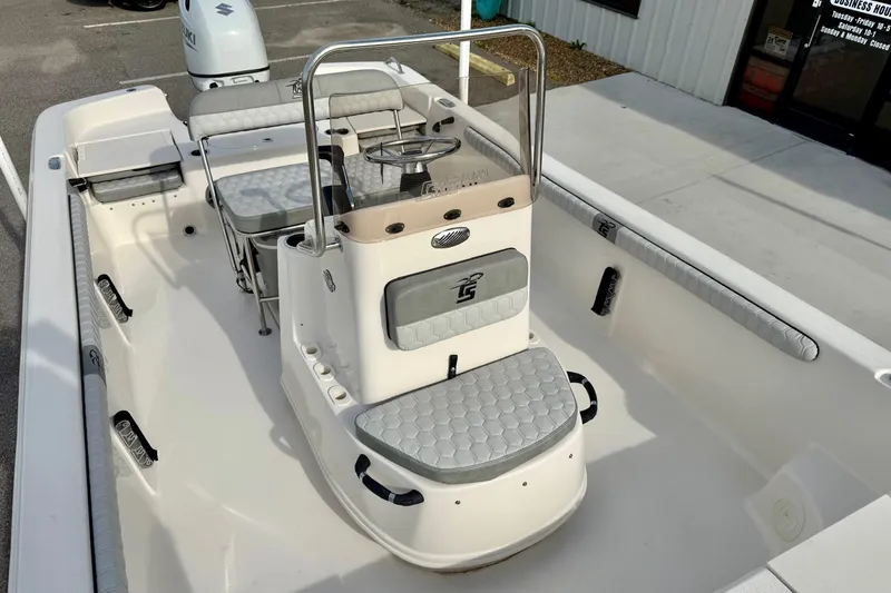 Slide: The Image of 2025 Carolina Skiff 19 LS boat interior with seating and console, parked outdoors. - 13