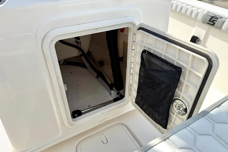 Slide: The Image of 2025 Carolina Skiff 19 LS boat storage compartment with open hatch and netted pocket. - 19