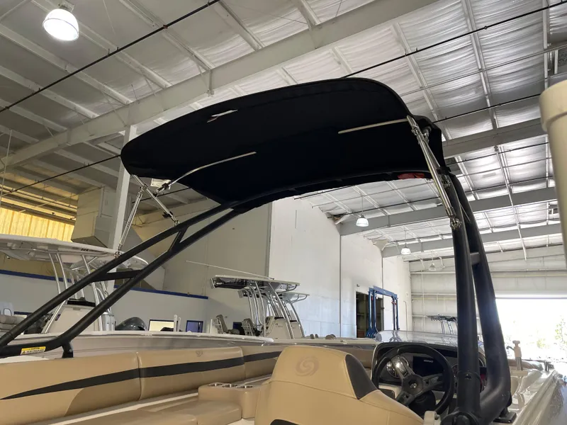 Slide: The Image of 2021 Hurricane SunDeck Sport 201 OB boat with black canopy in a storage facility. - 14