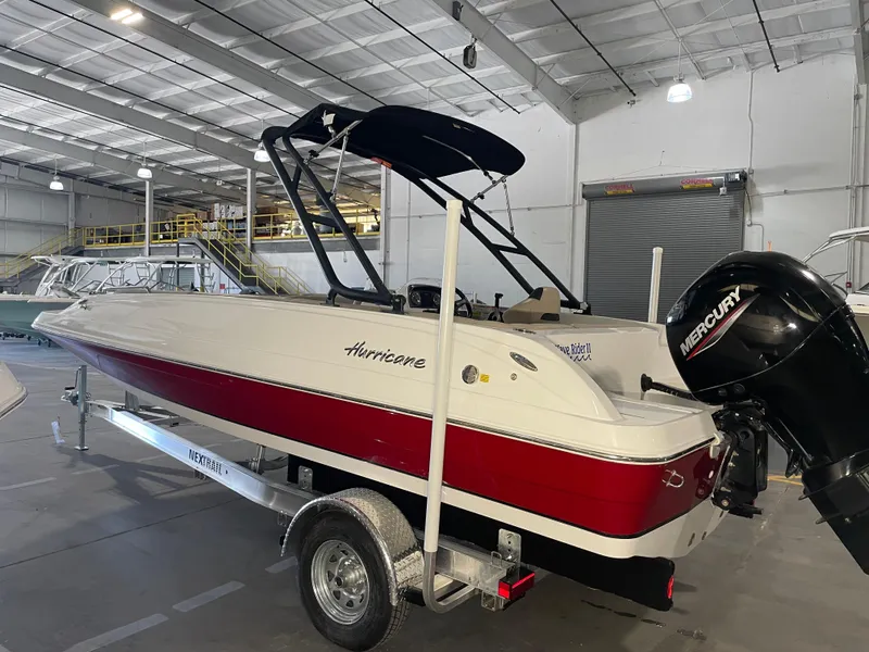 Slide: The Image of 2021 Hurricane SunDeck Sport 201 OB boat in a warehouse, featuring a red and white design. - 3