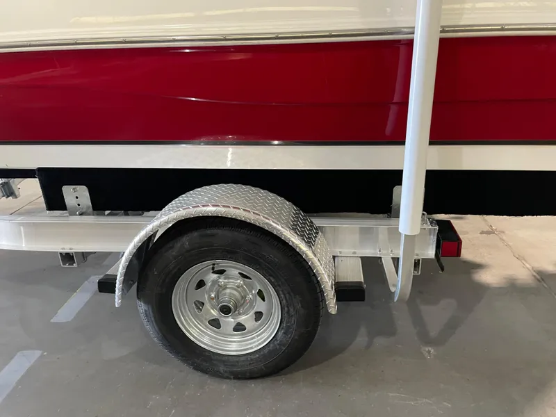 Slide: The Image of 2021 Hurricane SunDeck Sport 201 OB boat trailer with red and white hull, parked indoors. - 32