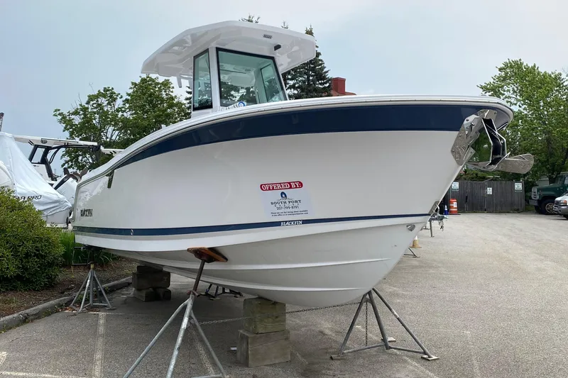 Slide: The Image of 2025 Blackfin 252 CC boat on display, elevated on stands in a parking area. - 2