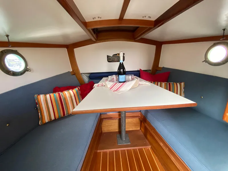 Slide: The Image of Cozy cabin interior of 1992 Devlin Surf Scoter with table, cushions, and portholes. - 13