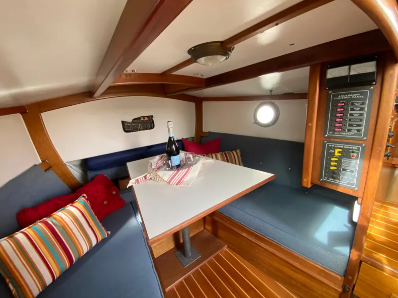 Slide: The Image of Cozy 1992 Devlin Surf Scoter boat interior with dining area, cushions, and control panel. - 14