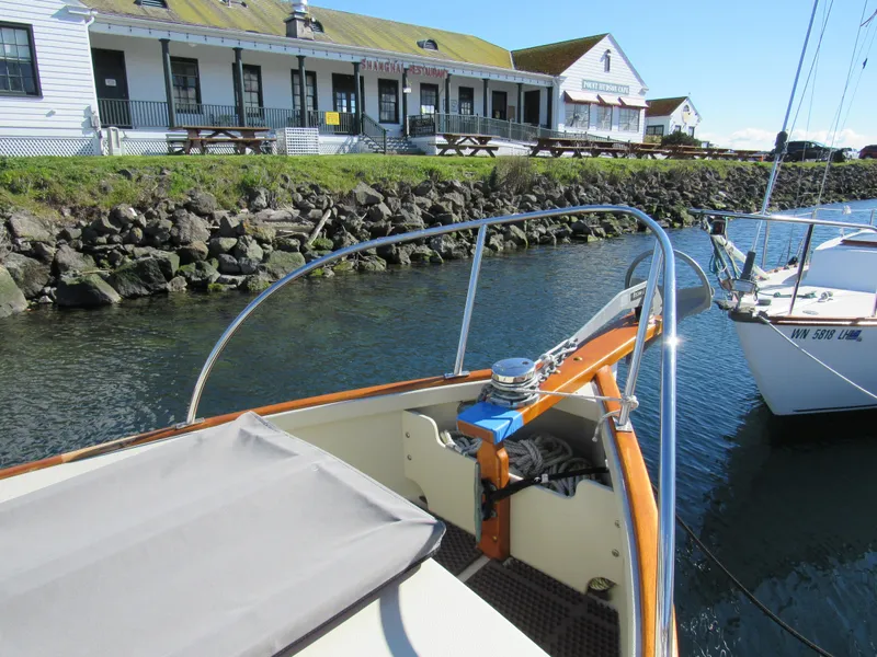 Slide: The Image of Devlin Surf Scoter 1992 boat docked near waterfront building and rocky shoreline. - 5