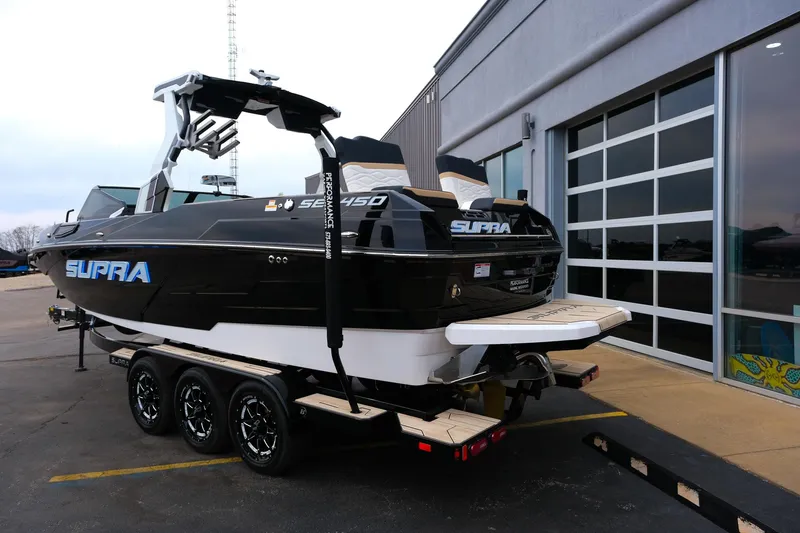 Slide: The Image of 2025 Supra SE450 boat on trailer, parked outside a building. - 4