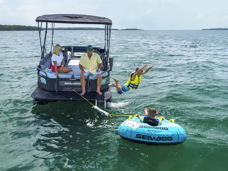 Slide: The Image of 2024 Sea-Doo Switch Cruise 21 on water, family enjoying tubing and swimming activities. - 9