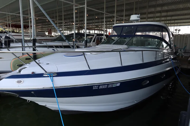 The Image of 2009 Crownline 340 CR boat docked in a marina, featuring sleek blue and white design. - 0