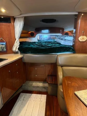 Slide: The Image of Interior of a 2009 Crownline 340 CR boat, featuring cozy sleeping area and wooden cabinetry. - 12