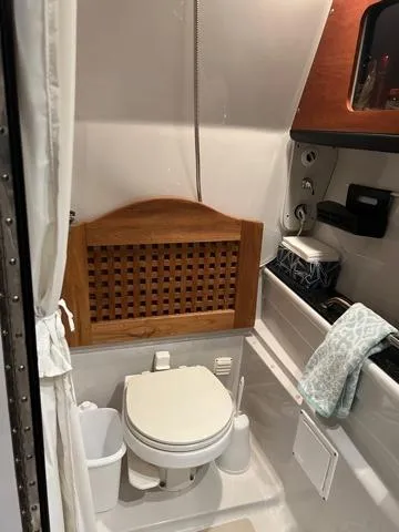 Slide: The Image of 2009 Crownline 340 CR boat bathroom with toilet, wooden accents, and storage shelves. - 13