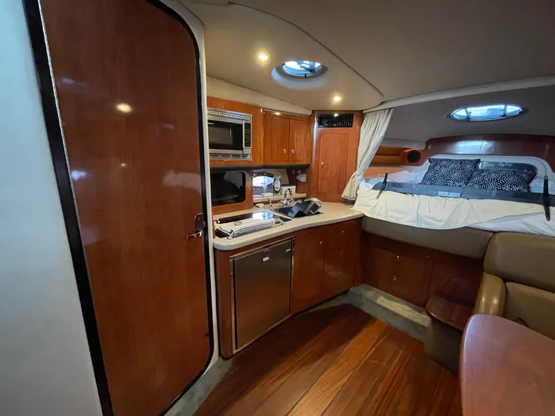 Slide: The Image of 2009 Crownline 340 CR cabin interior with wood finish, kitchenette, and cozy sleeping area. - 42