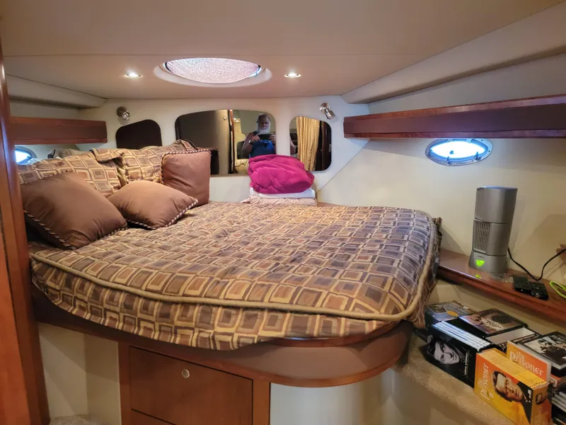 Slide: The Image of 2004 Cruisers Yachts 370 Express cabin with cozy bed, pillows, and ambient lighting. - 10