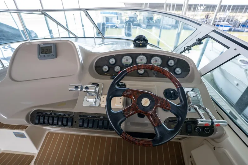 Slide: The Image of 2004 Cruisers Yachts 370 Express helm with wood-accented steering wheel and control panel. - 38