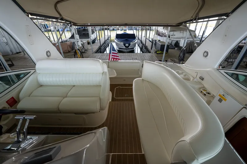Slide: The Image of 2004 Cruisers Yachts 370 Express interior with white seating and docked boats in background. - 40