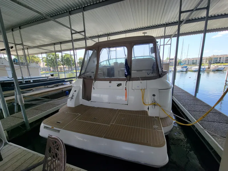 Slide: The Image of 2004 Cruisers Yachts 370 Express docked in a marina under a covered shelter. - 1