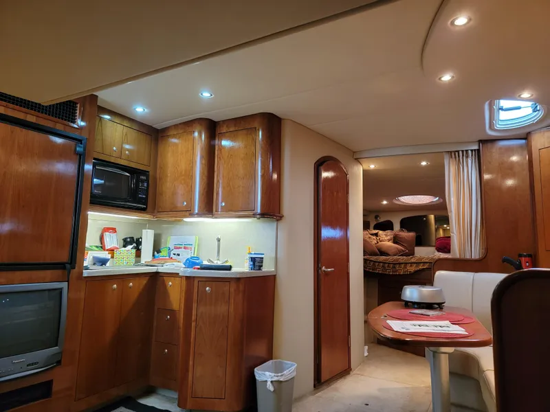 Slide: The Image of 2004 Cruisers Yachts 370 Express interior with wood cabinetry, kitchenette, and cozy seating area. - 13