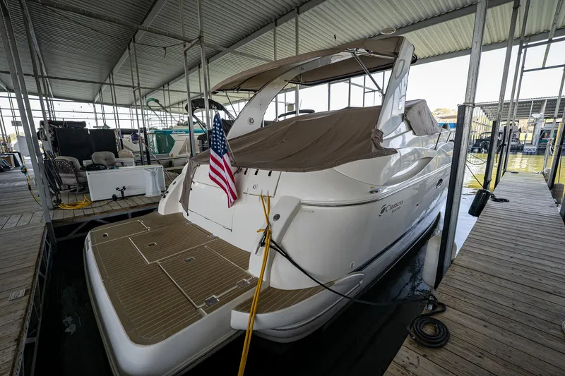 Slide: The Image of 2004 Cruisers Yachts 370 Express docked under a covered marina with an American flag. - 18