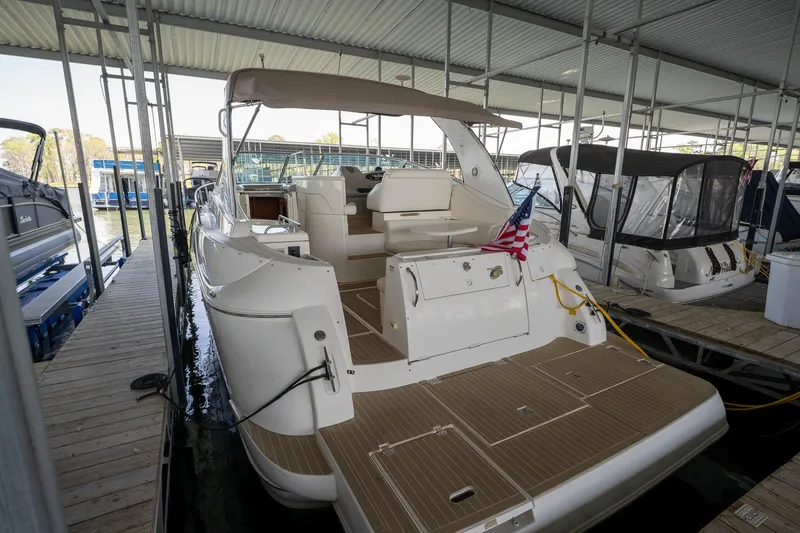 Slide: The Image of 2004 Cruisers Yachts 370 Express docked, featuring spacious deck and American flag. - 26