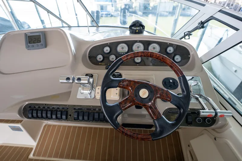 Slide: The Image of 2004 Cruisers Yachts 370 Express helm with wood-accented steering wheel and control panel. - 39