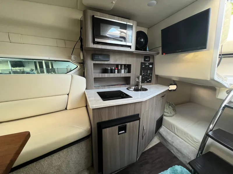 Slide: The Image of 2020 Regal 26 XO boat interior with kitchenette, microwave, and seating area. - 34