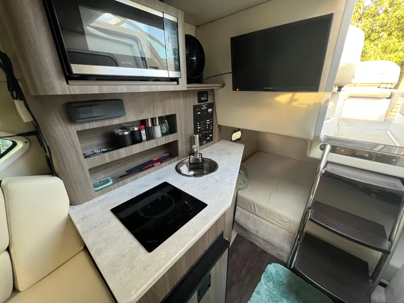 Slide: The Image of 2020 Regal 26 XO boat interior with kitchenette, microwave, TV, and seating area. - 35