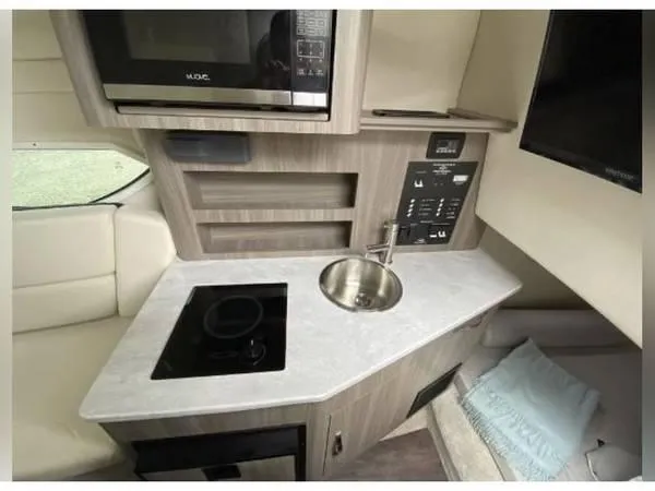 Slide: The Image of 2020 Regal 26 XO boat interior kitchen with sink, stove, and microwave. - 36