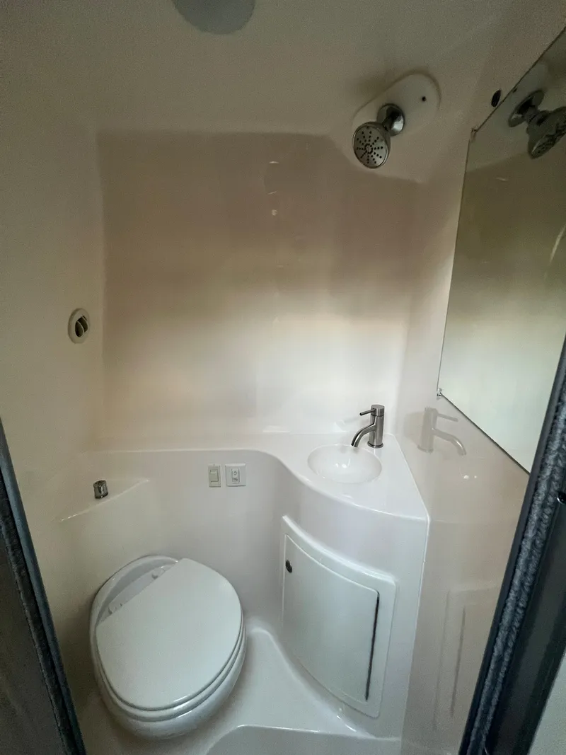 Slide: The Image of 2020 Regal 26 XO boat bathroom with compact toilet, sink, and showerhead. - 44