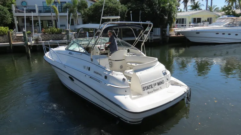 Slide: The Image of 1998 Doral 300 SC V Drive boat docked in a serene waterfront setting. - 10
