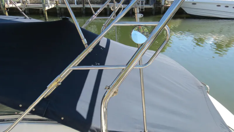 Slide: The Image of 1998 Doral 300 SC V Drive boat with chrome railings and black cover, docked by the water. - 17