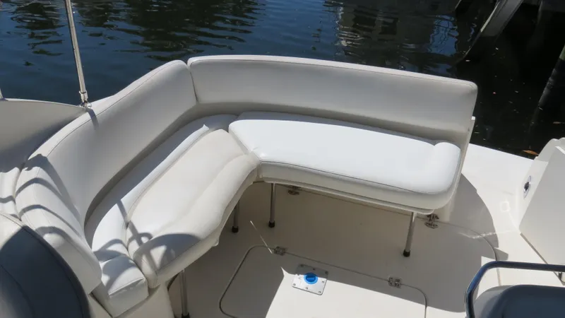 Slide: The Image of 1998 Doral 300 SC V Drive boat with white cushioned seating by the water. - 23