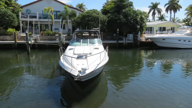 Slide: The Image of 1998 Doral 300 SC V Drive boat docked near waterfront homes with lush greenery. - 4