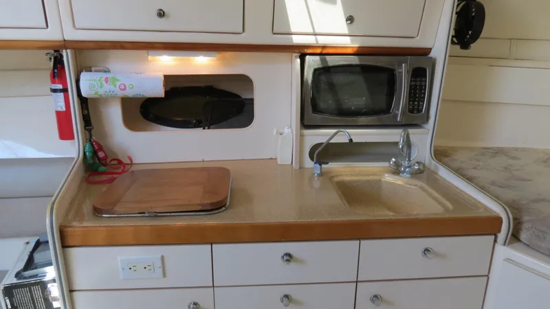 Slide: The Image of 1998 Doral 300 SC V Drive boat kitchen with sink, microwave, and storage cabinets. - 46