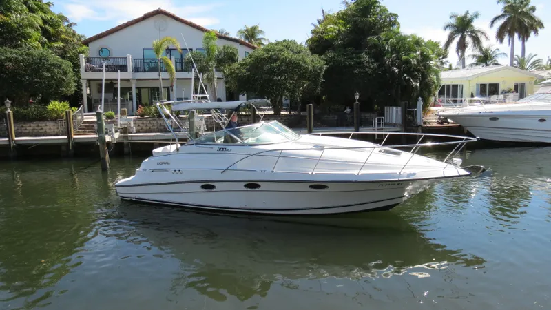 Slide: The Image of 1998 Doral 300 SC V Drive boat docked near waterfront homes with palm trees. - 5