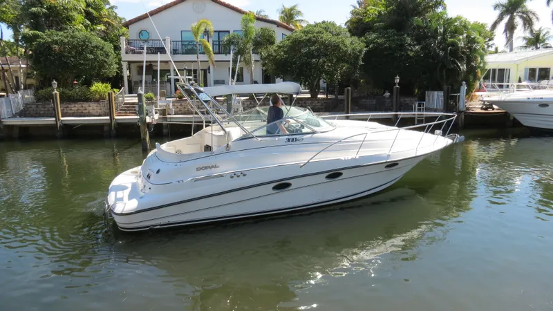 Slide: The Image of 1998 Doral 300 SC V Drive boat docked on a calm waterway near a house. - 7