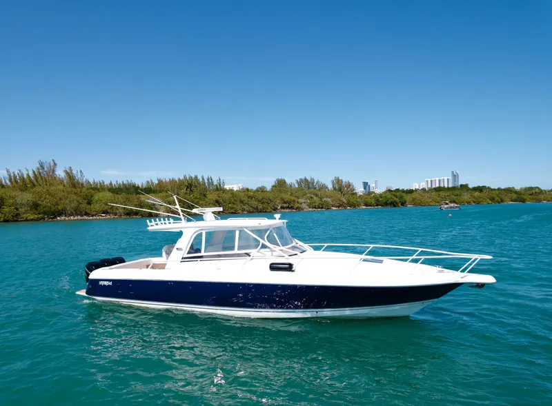 Slide: The Image of 2013 Intrepid 390 Sport Yacht on clear blue water, with lush green shoreline. - 1