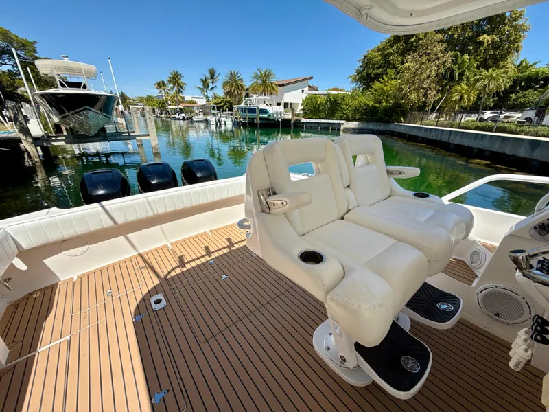Slide: The Image of 2013 Intrepid 390 Sport Yacht with dual white seats, docked by a scenic waterfront. - 13