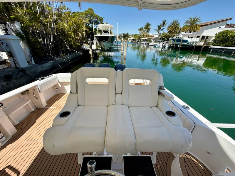 Slide: The Image of 2013 Intrepid 390 Sport Yacht with white seating, docked in a scenic marina. - 14