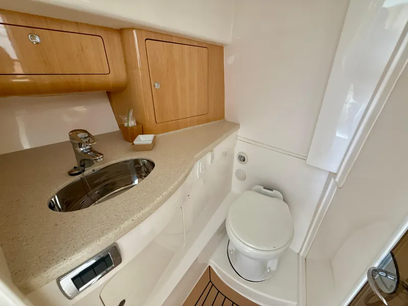 Slide: The Image of 2013 Intrepid 390 Sport Yacht bathroom with sink, toilet, and wooden cabinetry. - 22