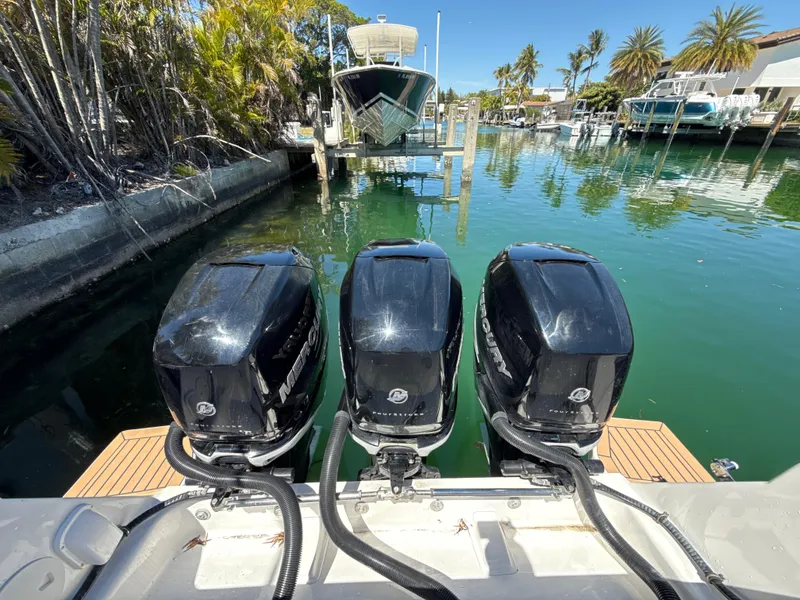 Slide: The Image of Three powerful outboard motors on a 2013 Intrepid 390 Sport Yacht, docked in a scenic marina. - 7