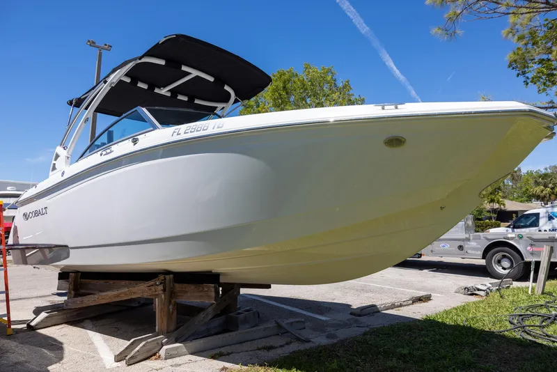Slide: The Image of 2019 Cobalt 25SC boat on display, white hull, parked outdoors on a sunny day. - 1