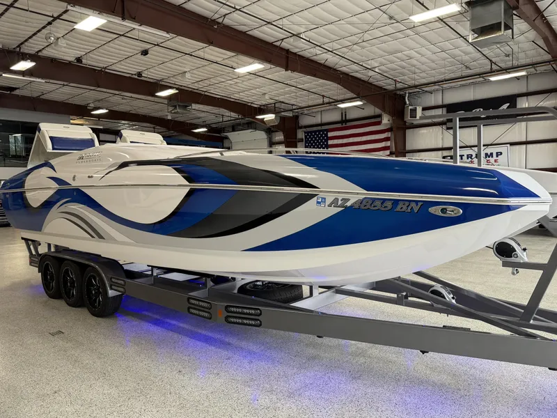 Slide: The Image of 2008 Magic 30' Sceptor boat with blue and white design on a trailer in a warehouse. - 14